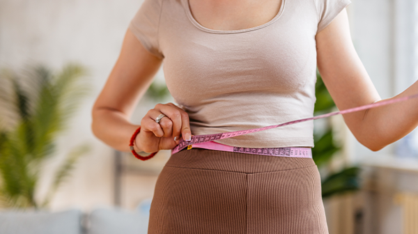 Eine Frau mit Maßband um den Bauch
