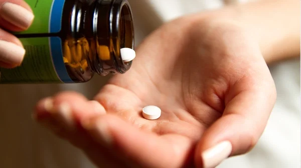 Hand mit weißen Tabletten