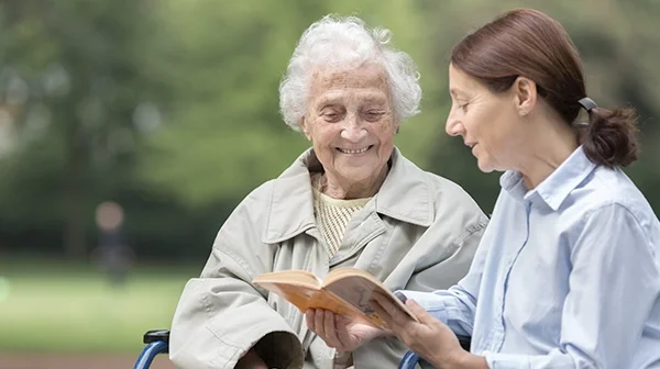 Alzheimer Patientin bekommt etwas vorgelesen von Ihrer Tochter