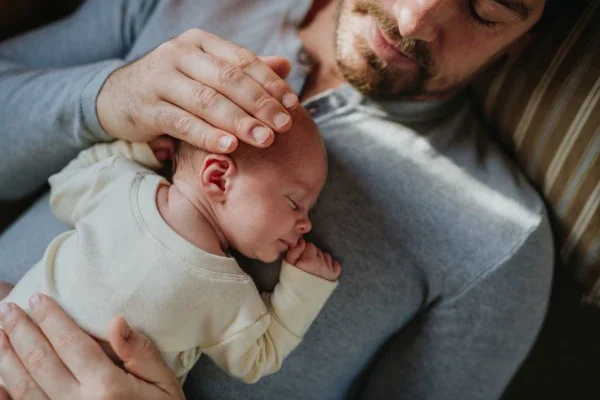 Ein Vater massiert sanft sein Baby gegen Blähungen