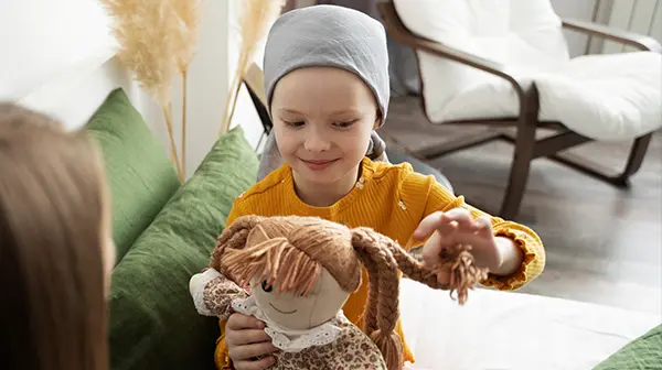 Kind mit Leukämie spielt fröhlich mit einem Kuscheltier