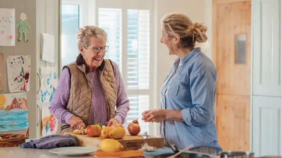 Haushaltshilfe hilft einer Seniorin in der Küche