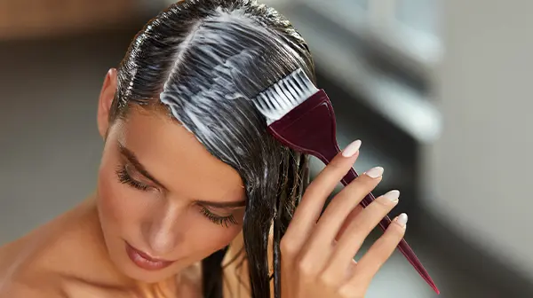 Eine Frau trägt mit einem Pinsel Haarfarbe in ihr Haar auf