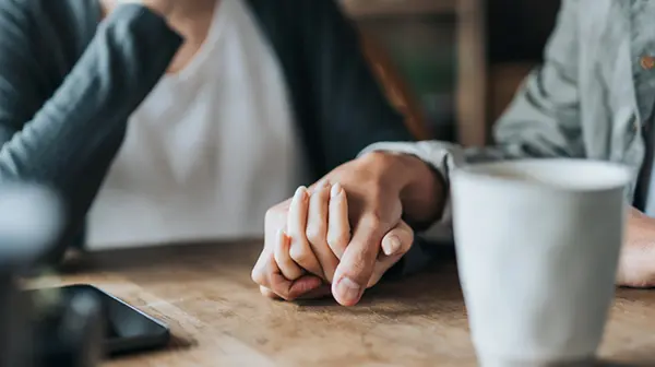 Person mit Depressionen hält hilfesuchend die Hand einer anderen Person