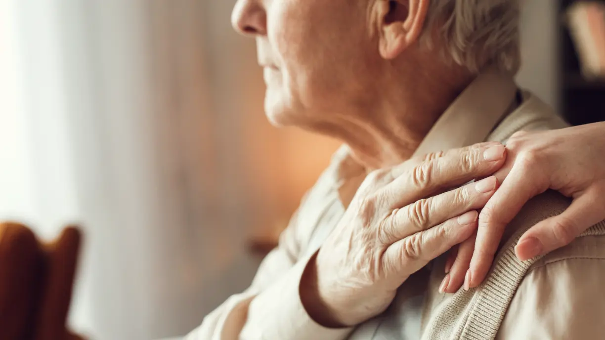 Pflegebedürftiger Mann hält die Hand seiner Tochter