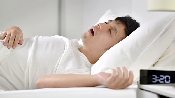 Mann liegt mit offenem Mund im Bett