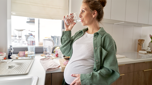 Hochschwangere Frau trinkt ein Glas Wasser